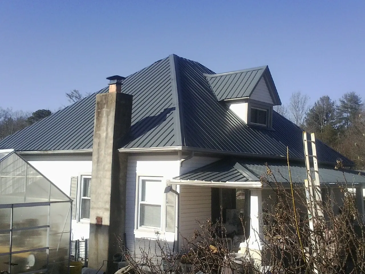 Dark blue standing seam metal roof on a white farmhouse with dormer — Slate & Tile Roof Repair by Roofing Brothers in Shelton