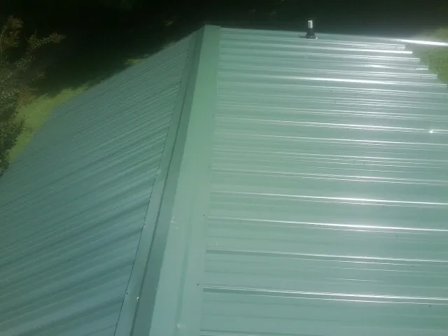 New green metal panels meeting at the ridge of a roof — Flat Roof Repair work by our crew in Shelton