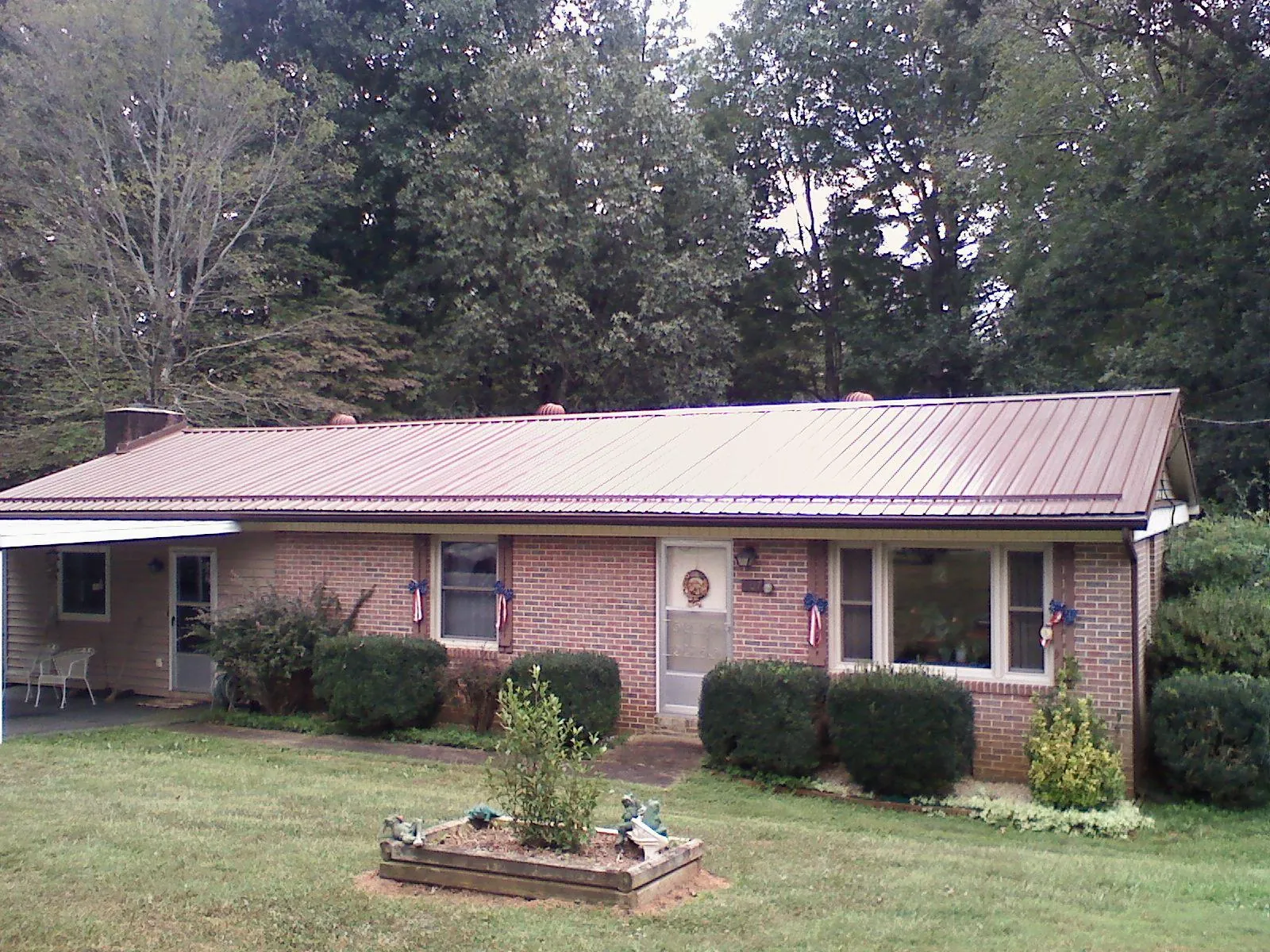 Bronze metal roof on a brick ranch home with a carport in Shelton