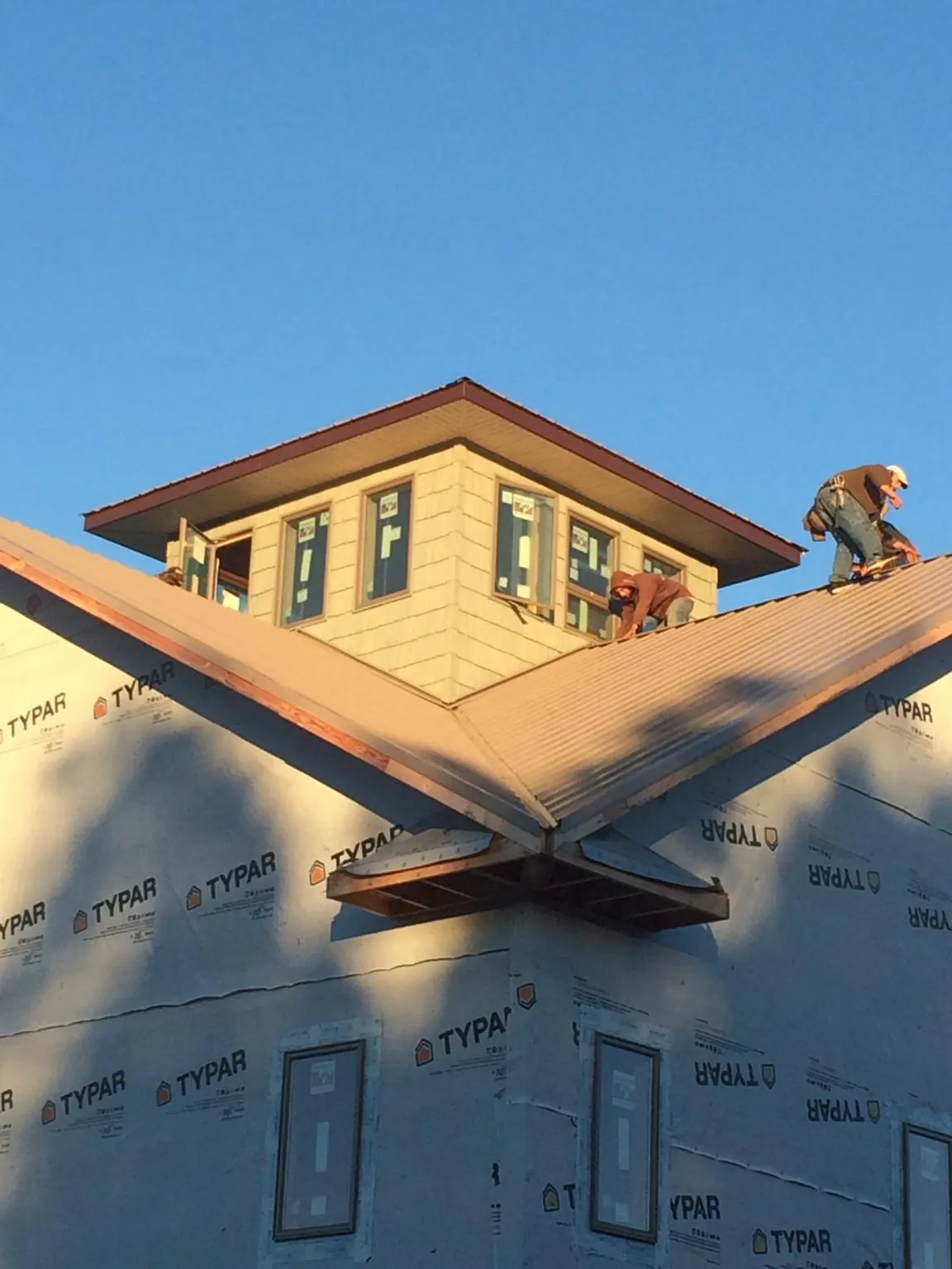 Roofers working around a rooftop cupola on a new metal roof at sunset — Roof Waterproofing in Shelton by Roofing Brothers